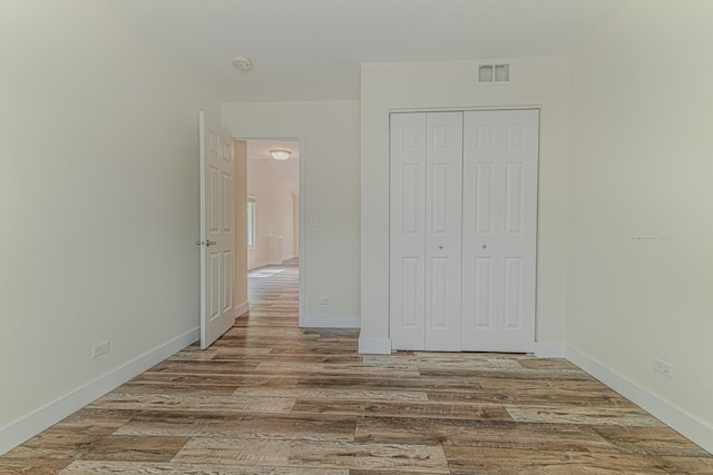 unfurnished bedroom with wood finished floors, a closet, and baseboards
