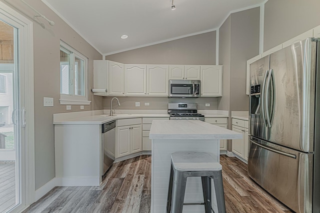 kitchen featuring appliances with stainless steel finishes, lofted ceiling, wood finished floors, light countertops, and white cabinets
