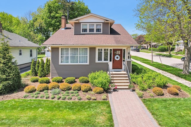 bungalow-style home with a front yard, a chimney, and roof with shingles