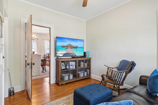 living room with wood finished floors, ornamental molding, a chandelier, baseboards, and ceiling fan