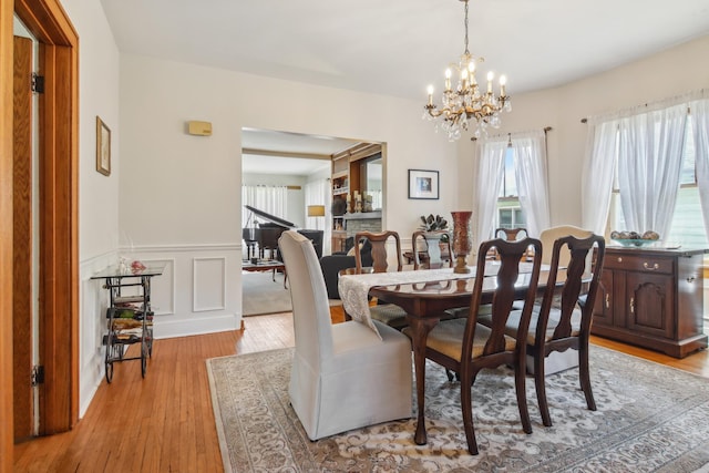 dining room featuring a chandelier, light wood-type flooring, and wainscoting