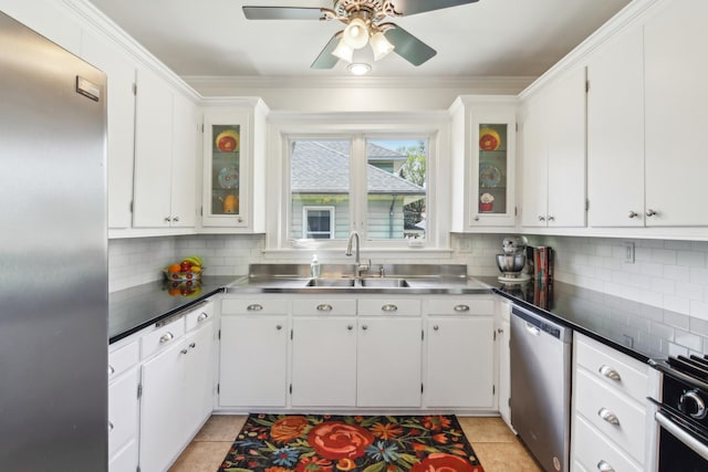 kitchen with stainless steel countertops, stainless steel appliances, a sink, a ceiling fan, and tasteful backsplash
