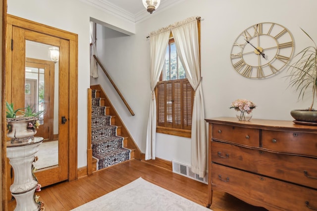 entrance foyer with wood finished floors, stairs, ornamental molding, and baseboards