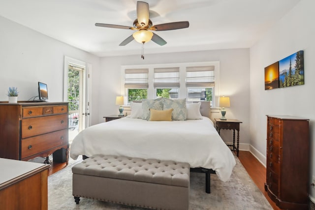 bedroom featuring multiple windows, baseboards, access to exterior, and wood finished floors
