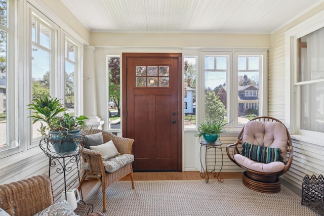 sunroom featuring healthy amount of natural light, ornamental molding, and wood finished floors