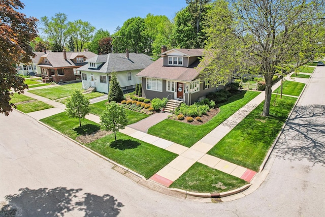 bungalow-style home featuring a chimney, a front lawn, and driveway