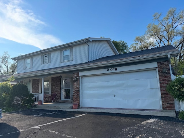 view of front of property featuring brick siding, a porch, driveway, and an attached garage