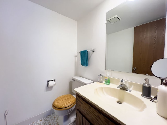 bathroom featuring toilet, vanity, and baseboards