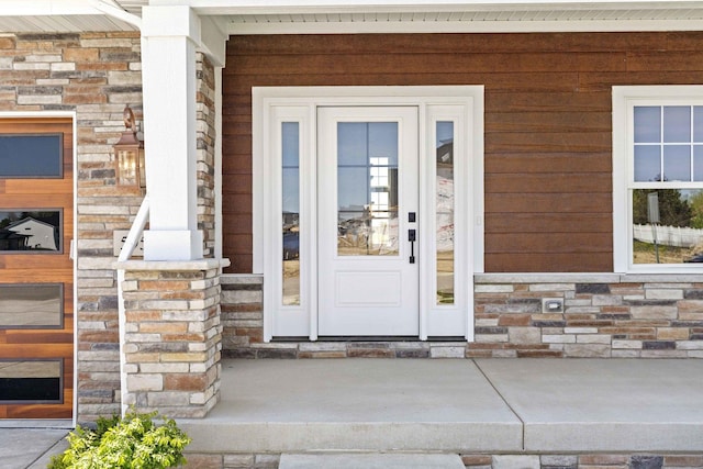 property entrance with stone siding and a porch