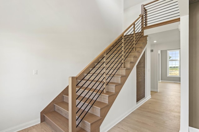 staircase featuring wood finished floors and baseboards
