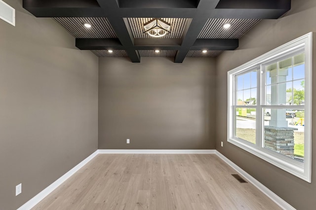 unfurnished dining area with wood finished floors, coffered ceiling, beam ceiling, plenty of natural light, and baseboards
