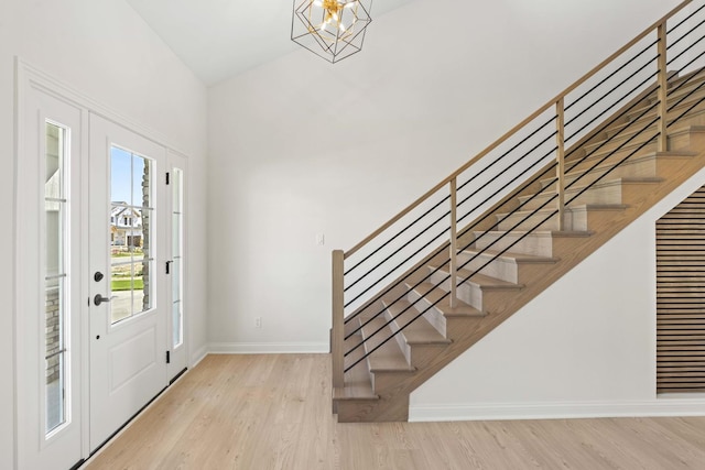 entrance foyer featuring stairs, baseboards, wood finished floors, and a chandelier
