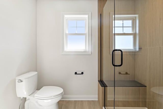 bathroom with a shower stall, toilet, and baseboards