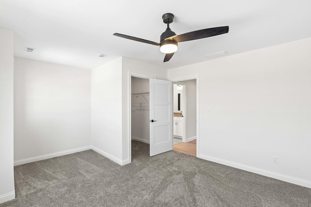 unfurnished bedroom featuring carpet floors, a spacious closet, baseboards, a closet, and a ceiling fan