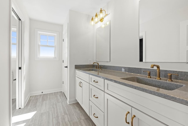 full bath with double vanity and baseboards
