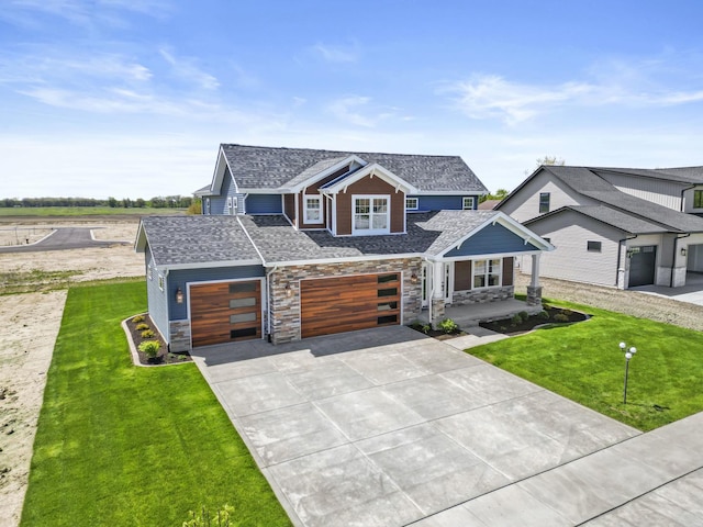 view of front facade with a front lawn, concrete driveway, stone siding, and an attached garage