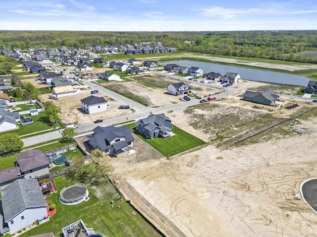 aerial perspective of suburban area with a nearby body of water and a heavily wooded area