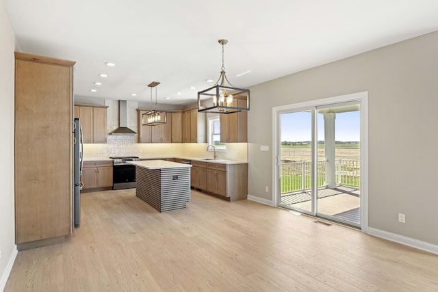 kitchen with wall chimney exhaust hood, stainless steel appliances, baseboards, light countertops, and light wood-style flooring