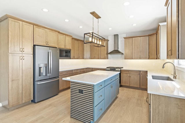 kitchen featuring stainless steel appliances, wall chimney range hood, a sink, light wood-style floors, and recessed lighting