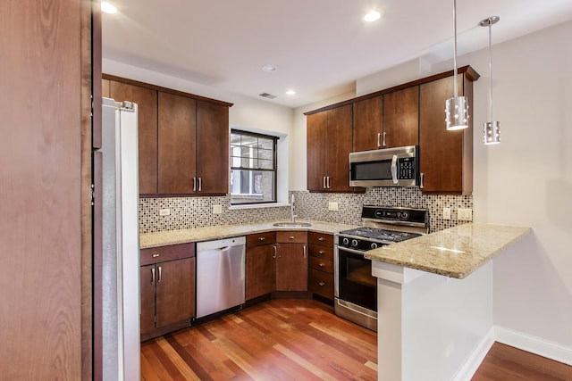 kitchen with stainless steel appliances, decorative backsplash, light wood-style floors, a peninsula, and recessed lighting