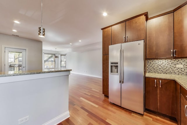 kitchen with stainless steel fridge with ice dispenser, tasteful backsplash, light wood-style flooring, light stone countertops, and recessed lighting