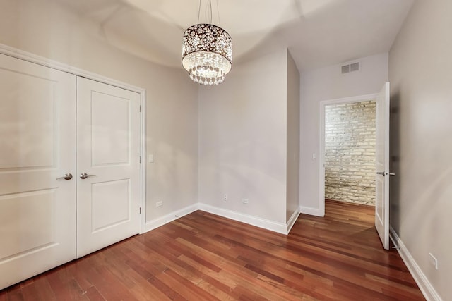 unfurnished dining area featuring wood finished floors, a chandelier, and baseboards