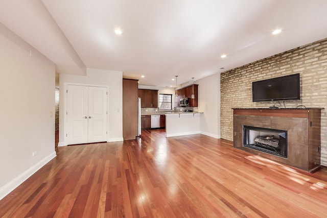 unfurnished living room with wood finished floors, a fireplace, baseboards, and recessed lighting
