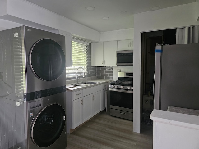 216 Washington St, Park Forest, IL 60466 - kitchen featuring stainless steel appliances, estacked washer and dryer, a sink, and white cabinetry