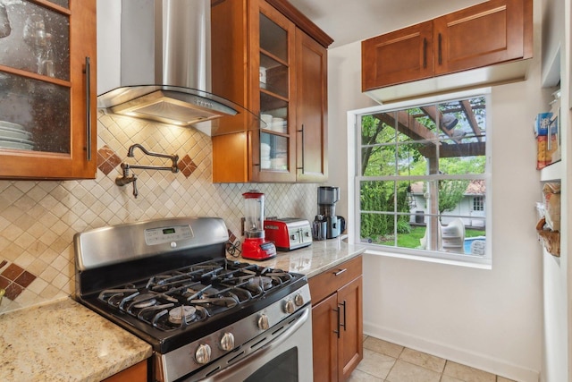 89 Huron St, Maywood, IL 60153 - kitchen with stainless steel gas range oven, wall chimney exhaust hood, light stone counters, backsplash, and baseboards
