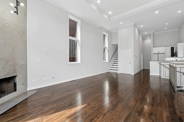 1018 N Honore Ave Unit C, Chicago, IL 60622 - unfurnished living room featuring crown molding, dark wood finished floors, a stone fireplace, stairway, and recessed lighting