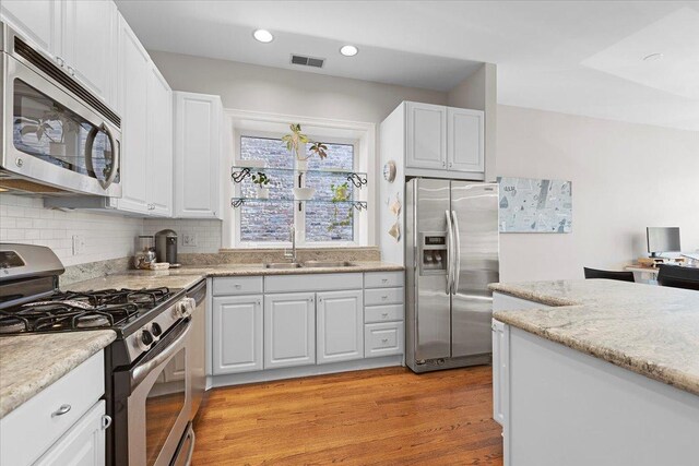 3616 N Janssen Ave Unit 2N, Chicago, IL 60613 - kitchen with stainless steel appliances, a sink, light wood-style flooring, backsplash, and white cabinetry