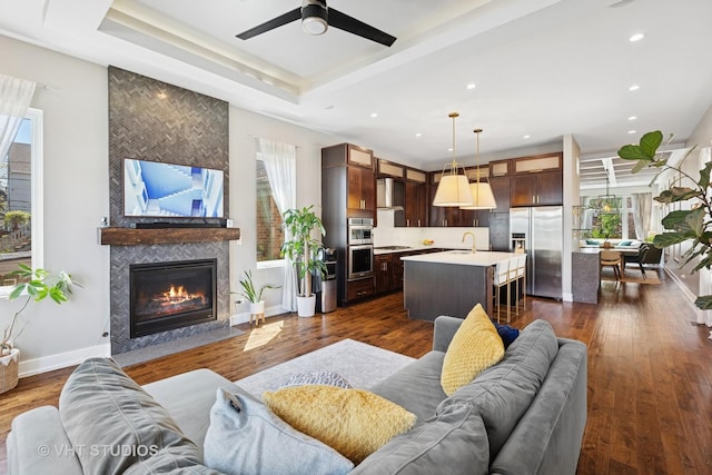living area featuring plenty of natural light, a fireplace, a ceiling fan, recessed lighting, and dark wood finished floors