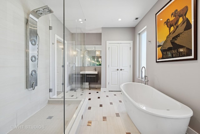 bathroom with a shower stall, a soaking tub, vanity, and recessed lighting