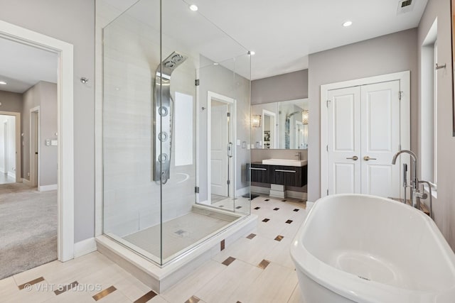 bathroom with a shower stall, a freestanding tub, vanity, baseboards, and recessed lighting