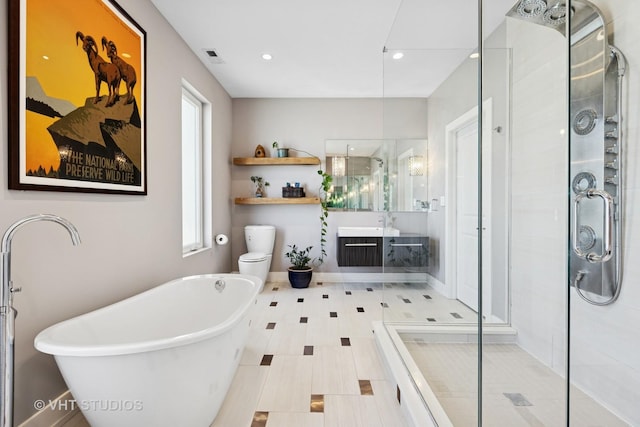 bathroom with a shower stall, a freestanding bath, vanity, recessed lighting, and toilet