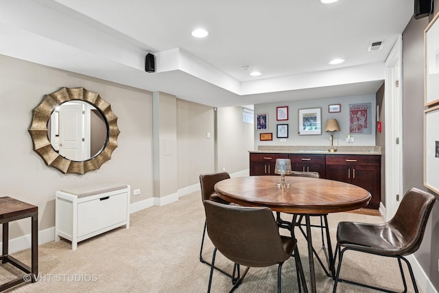 dining space with bar with sink, light colored carpet, baseboards, and recessed lighting