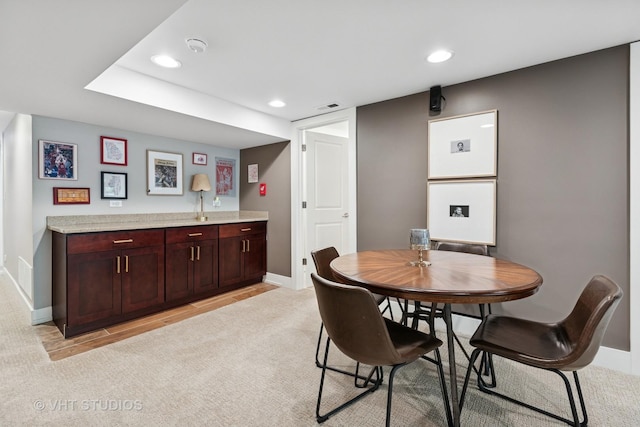 dining area with baseboards, light carpet, recessed lighting, and bar