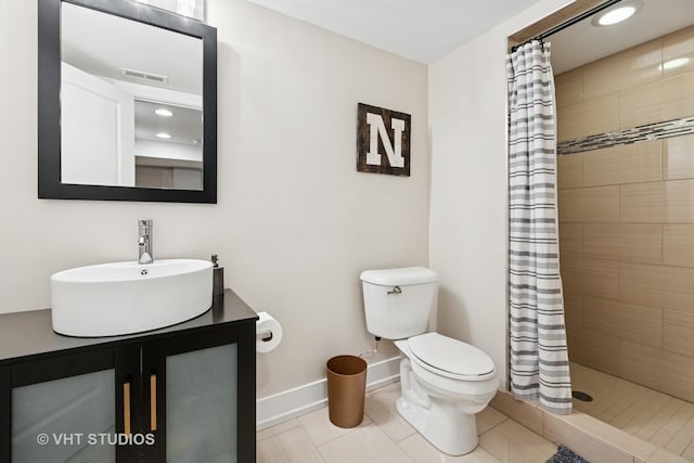 bathroom with toilet, a tile shower, baseboards, and vanity