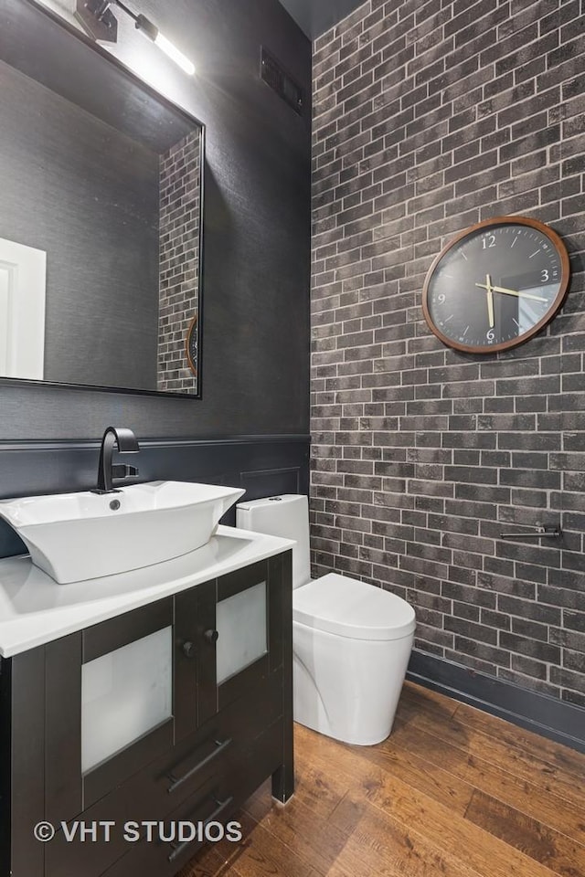 half bath with wood finished floors, toilet, and vanity