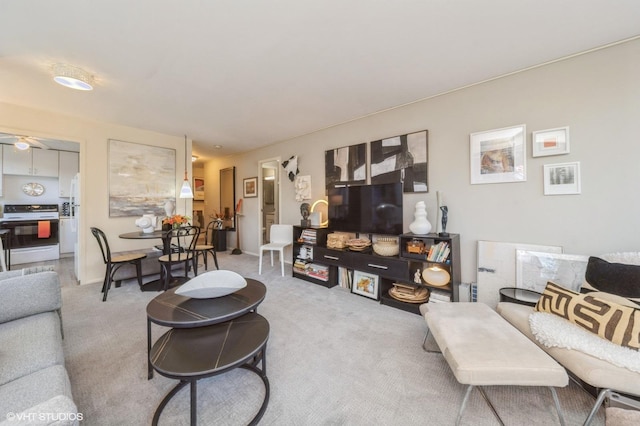 carpeted living area with ceiling fan