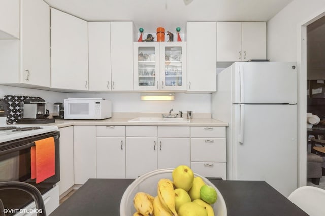 kitchen featuring white appliances, a sink, white cabinetry, and light countertops