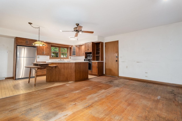 937 Twilight Ln, Wheeling, IL 60090 - kitchen with appliances with stainless steel finishes, brown cabinets, light wood-style flooring, and a center island