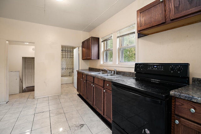 1990 Patrick Ave, Kankakee, IL 60901 - kitchen with black electric range, a sink, dark countertops, light tile patterned floors, and dark brown cabinetry