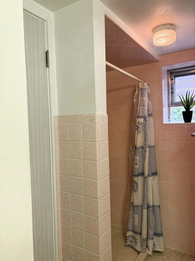bathroom with a tile shower and tile walls