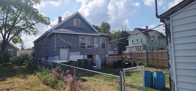 1128 N Hickory St, Joliet, IL 60435 - back of property with a fenced backyard, a chimney, and a shingled roof