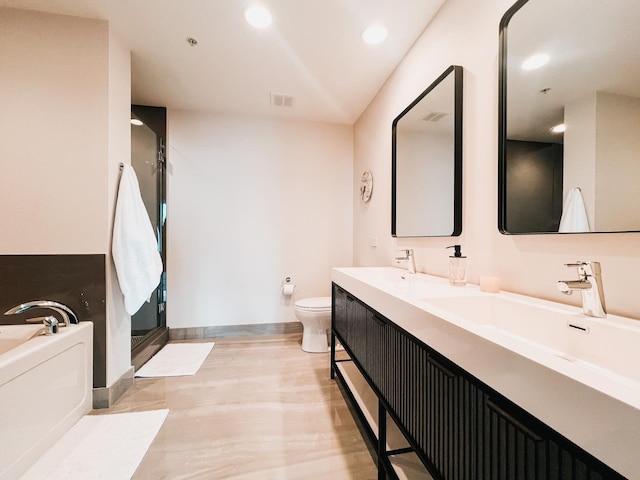 bathroom featuring toilet, a bath, a shower stall, double vanity, and recessed lighting