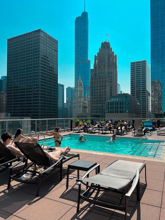 community pool featuring a patio, a view of skyline, and fence
