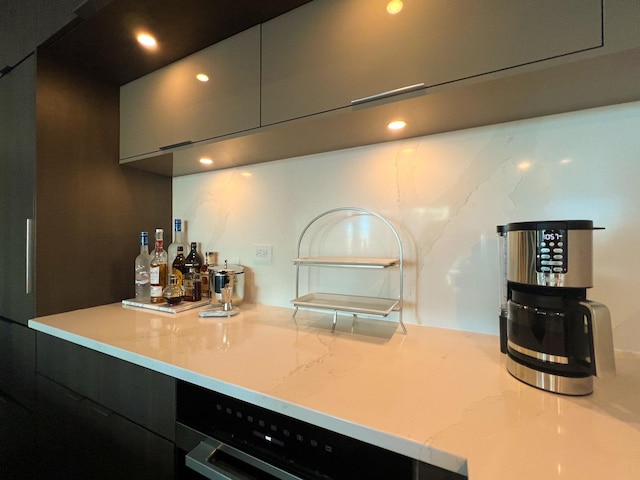 kitchen featuring modern cabinets, dishwashing machine, recessed lighting, and light stone counters