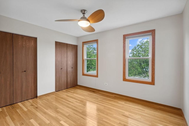 1836 71st St, Woodridge, IL 60517 - unfurnished bedroom with multiple closets, light wood-style floors, baseboards, and ceiling fan