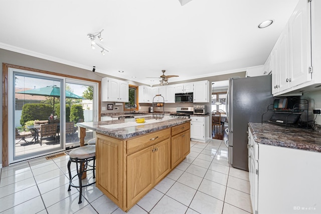 19634 Patricia Ln, Mokena, IL 60448 - kitchen featuring appliances with stainless steel finishes, ornamental molding, light tile patterned floors, a kitchen bar, and white cabinetry